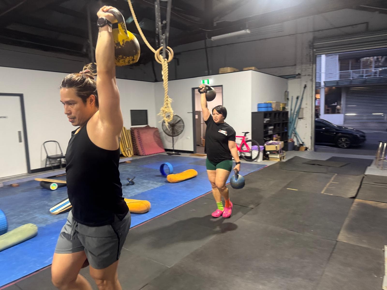 Two members pressing kettlebells overhead together