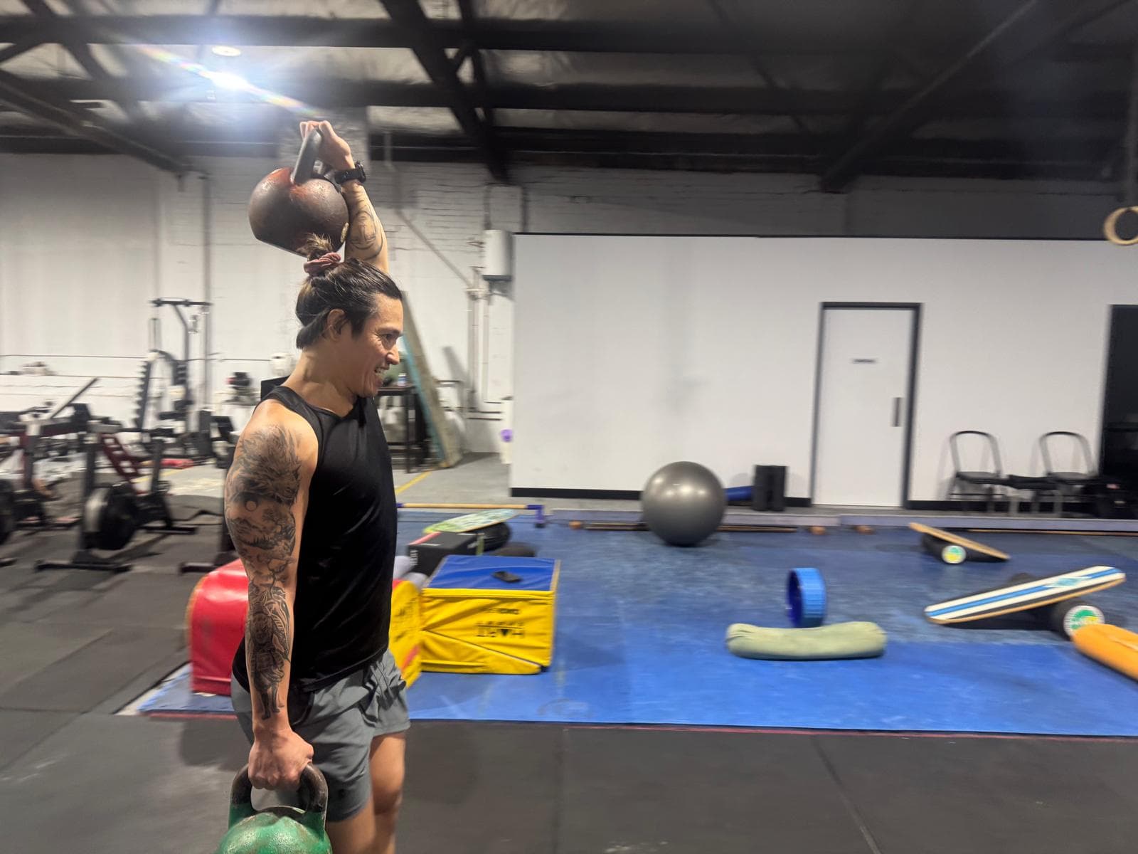 A member holding a kettlebell overhead