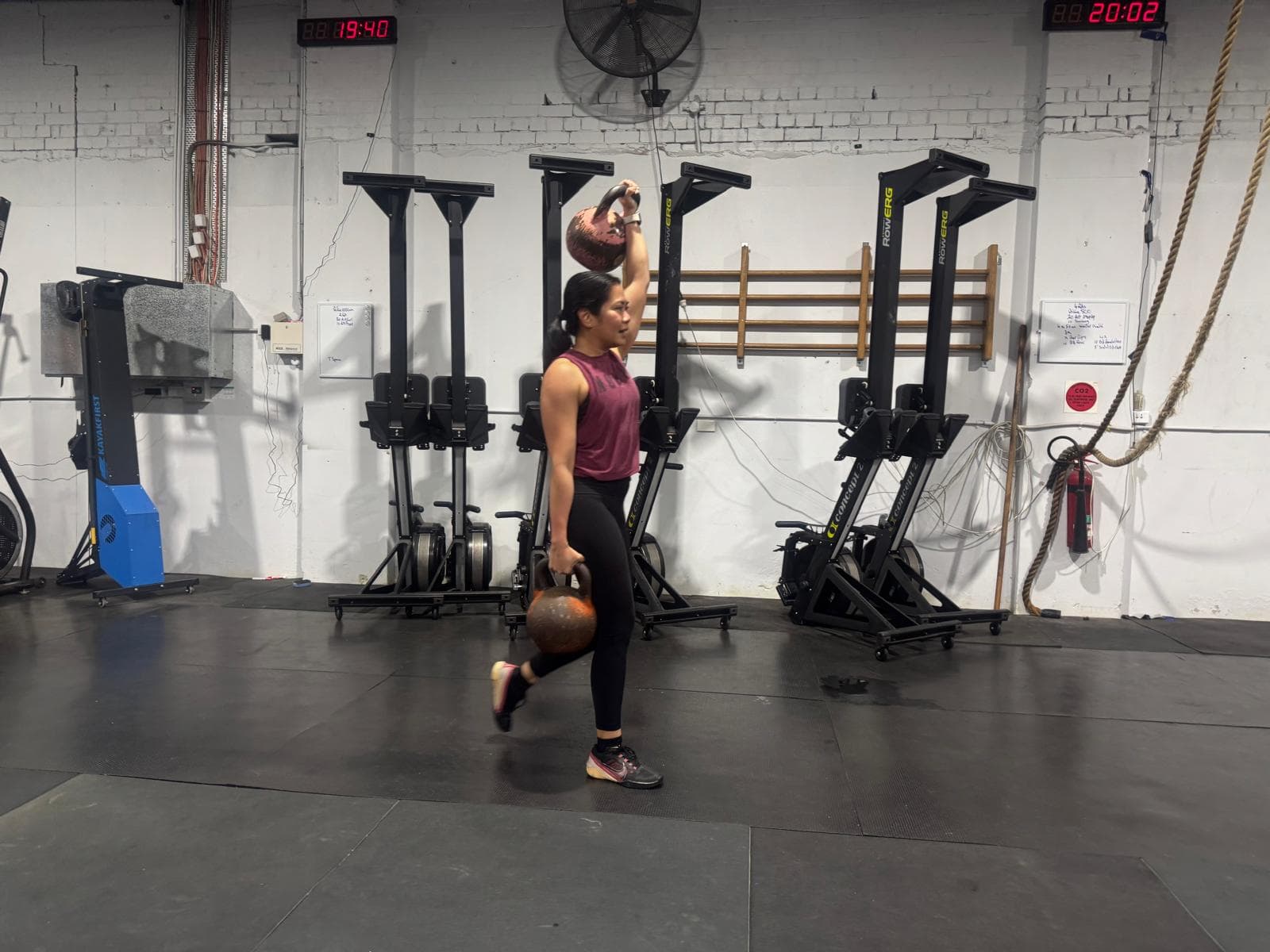A member lunging with a kettlebell held overhead