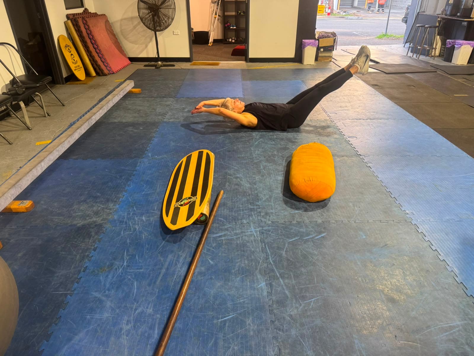 A member doing a floor mobility and core exercise on mats