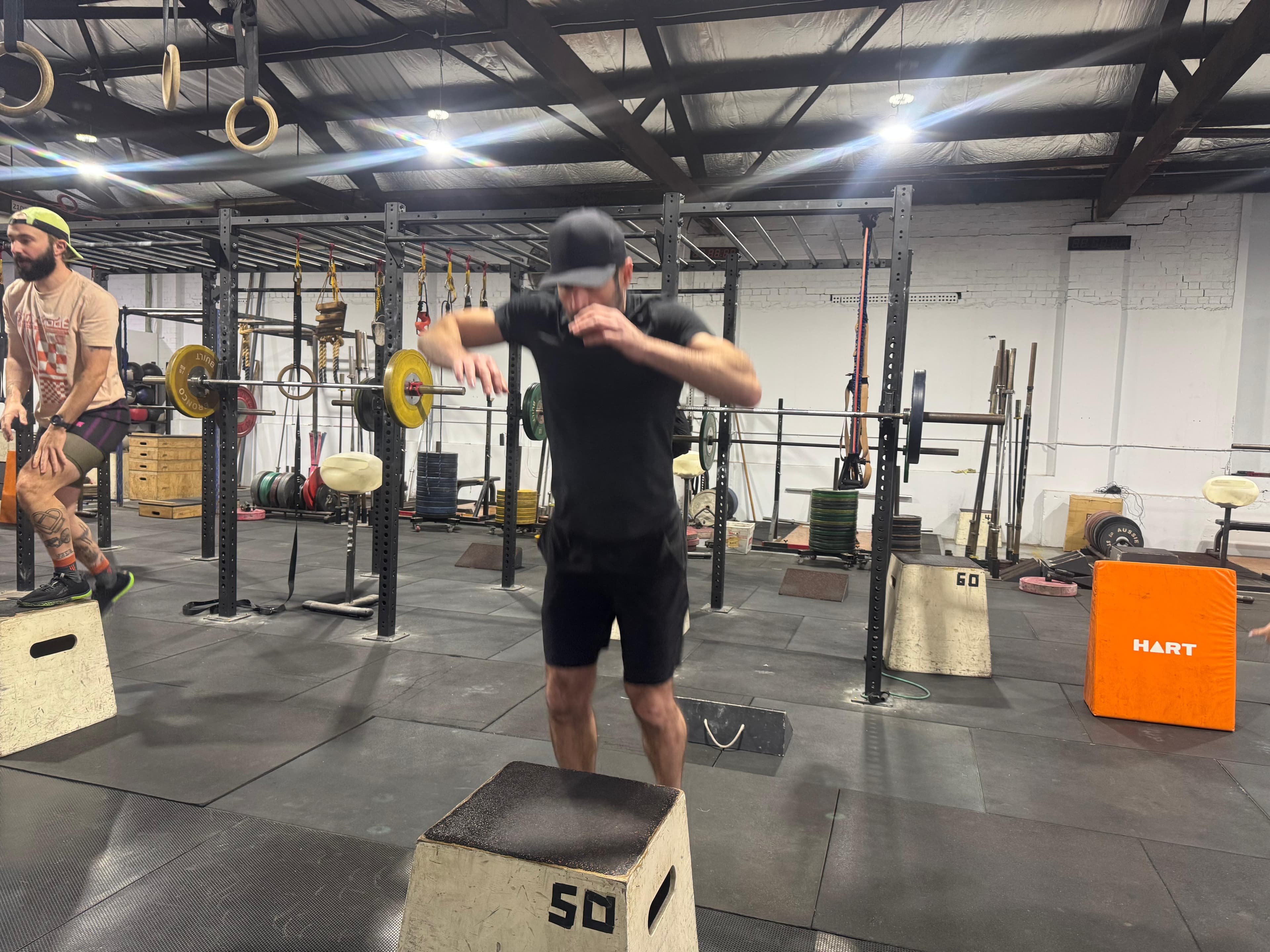 A member mid box-jump on the gym floor